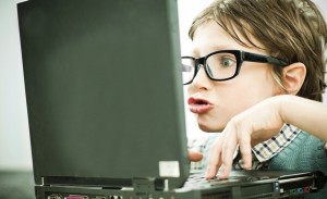 Funny looking boy geek using his laptop.